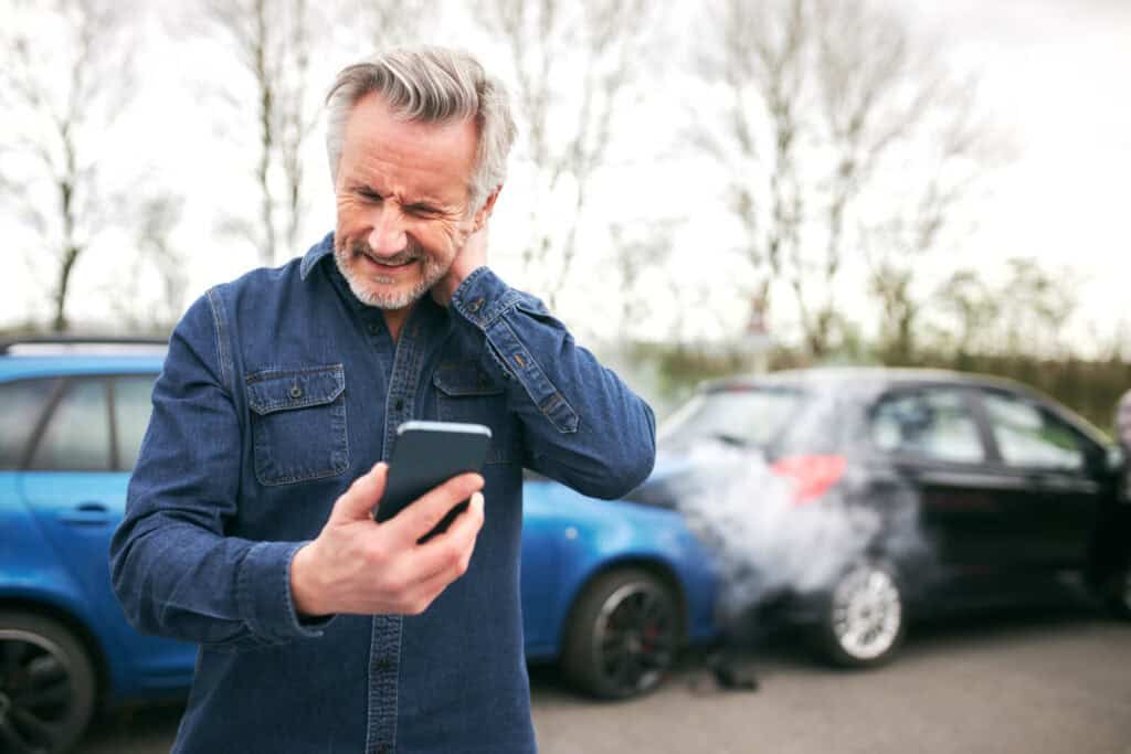 An older man holding his phone | Tips for getting rid of tech neck