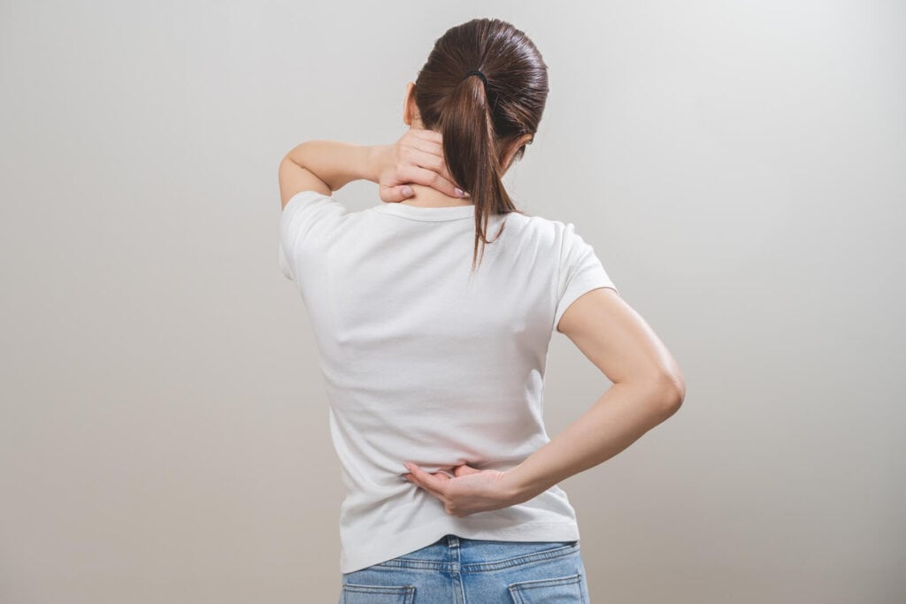 A woman holding her back in pain | Tips for getting rid of tech neck